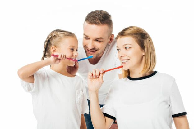 Happy family brushing their teeth together, teaching good oral hygiene habits