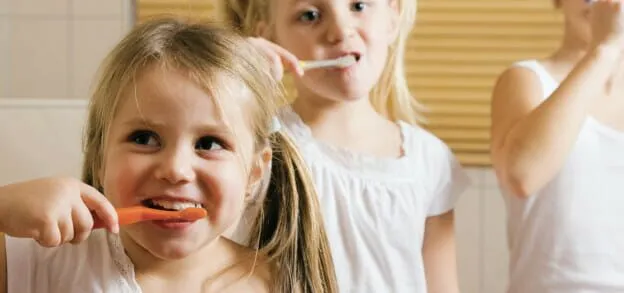 Young children brushing their teeth together in a bathroom